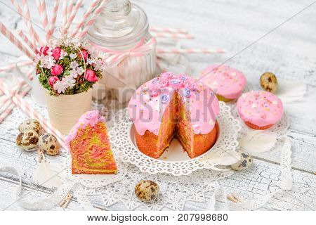 Traditional Easter cake with decorations and cupcakes on wooden table