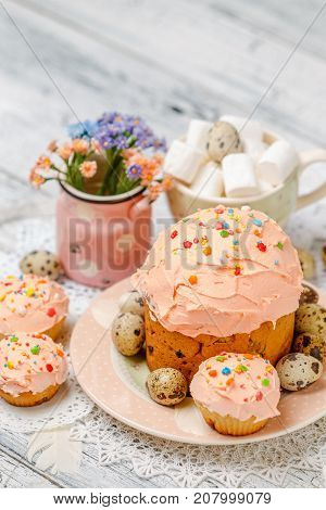 Traditional Easter cake with decorations and cupcakes on wooden table