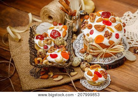 Traditional Easter cake with decorations and cupcakes on wooden table