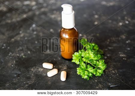 Brown Glass Bottle With Essential Oil Or Creme, Vitaminen And Healing Green Plant On The Dark Rough 