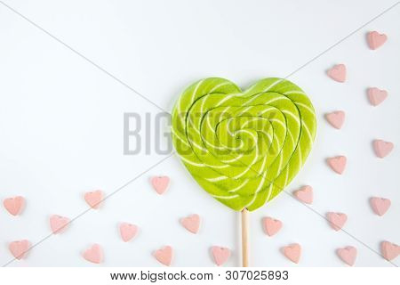 Spiral Heart Lollipop On Whitel Background Among Small Pink Heart-shaped Candies