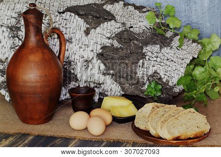 Sheep Cheese, Rye Fresh Bread On Ceramic Plate, Eggs, Clay Jug For Wine And Cup On Coarse Sackcloth 