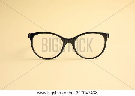 Modern Fashionable Acetate Spectacles, Black Color, Laying On Light Yellow Background.