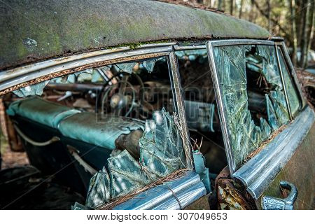 Old Decaying Car Showing Broken Glass Windows And Rotting Interior That Is Abandoned At A Salvage Ya