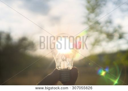 First Person View Of Person Hold Light Bulb Outside At The Nature, Enegry Concept With A Sunshine Th