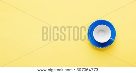 Blue Coffee Cup And Sauser On Yellow Background Table, Top View, Copy Space, Selective Focus