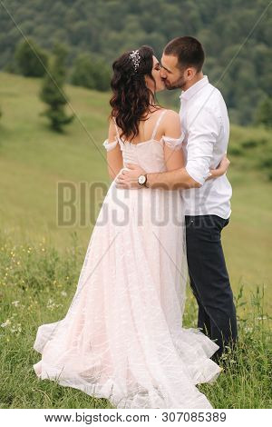 Beautiful Young Wedding Couple Standing On The Green Slope, Hill. Groom And Bride In Carpathian Moun