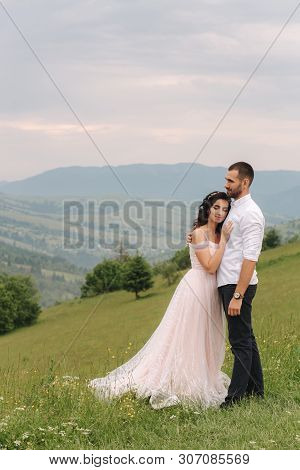 Beautiful Young Wedding Couple Standing On The Green Slope, Hill. Groom And Bride In Carpathian Moun
