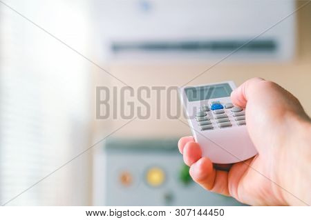 Remote Control. Male Hand With Air Conditioning Remote Control. The Man Switches The Modes Of Condit