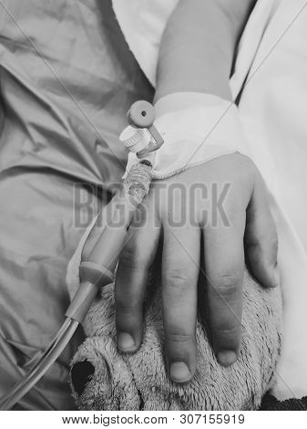 Black And White Photo With The Hand Of An Ill Little Girl In A Pediatric Hospital Reserve, With A Ca