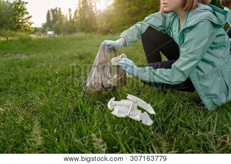 Blogging Concept. The Girl Collects Trash From The Forest In The Trash Bag