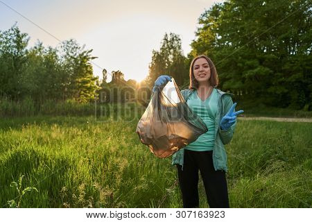Blogging Concept. The Girl Collects Trash From The Forest In The Trash Bag