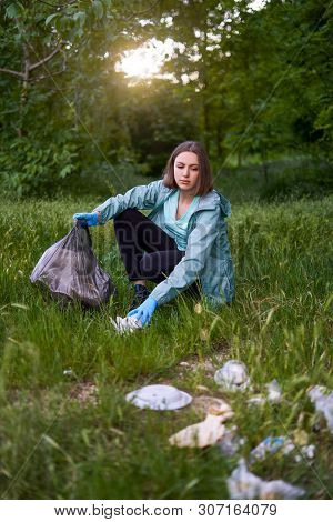 Blogging Concept. The Girl Collects Trash From The Forest In The Trash Bag