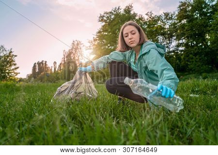Blogging Concept. The Girl Collects Trash From The Forest In The Trash Bag