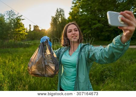 Blogging Concept. The Girl Collects Trash From The Forest In The Trash Bag