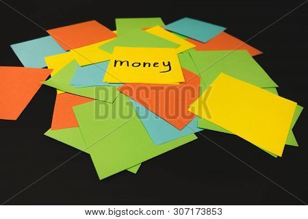 The Word Money On A Piece Of Yellow Paper Among Multicolored Paper