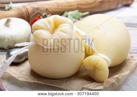 Italian Provolone Or Provola Caciocavallo Hard Cheeses In Teardrop Form Served On Old Paper Close Up