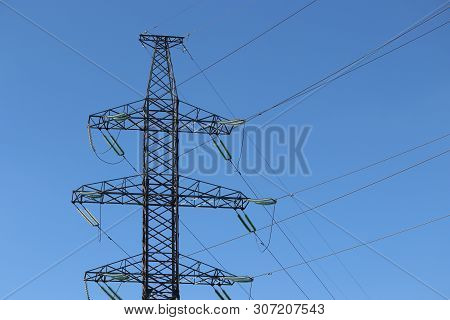 High Voltage Power Line Supports With Electrical Wires Isolated On Blue Sky. Electricity Transmissio