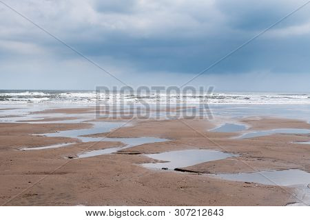 Minimalist Image Of A Flat Sandy Beach At Filey, North Yorkshire, With Numerous Puddles Left Behind 