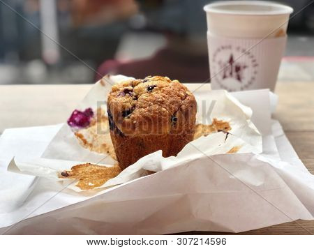 LONDON, UK - JUNE 19, 2019: A Berry muffin and paper packaging with coffee inside a Pret A Manger cafe in London, UK.