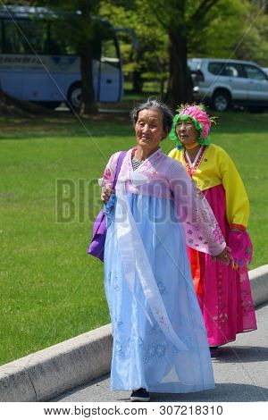 Pyongyang, North Korea - May 1, 2019: An Old Women In Traditional Korean Clothes Walking In The Taes