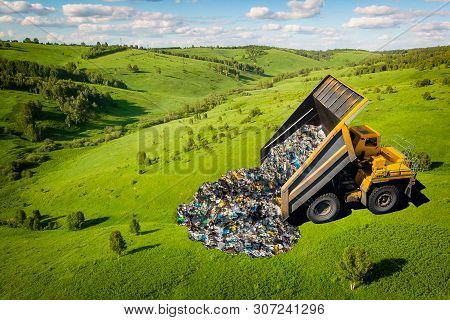Garbage Truck Dumps Plastic Waste And Packages Onto Clean Green Field. Concept Pollution Of Environm