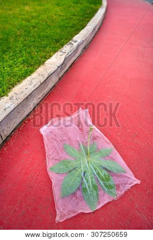 Concept of pollution by plastic asphyxiating nature on red sidewalk garden
