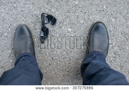 View Of The Feet Of A Man Who Stands On An Asphalt Road On The Background Of Fallen And Broken Sun G