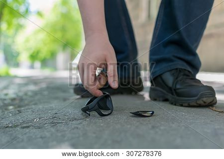 View Of A Man Feet On A City Street That Stands On An Asphalt Pedestrian Road And Raises Fallen And 