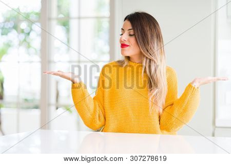 Young beautiful woman wearing winter sweater at home Smiling showing both hands open palms, presenting and advertising comparison and balance