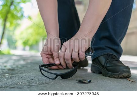 View Of A Man Feet On A City Street That Stands On An Asphalt Pedestrian Road And Raises Fallen And 