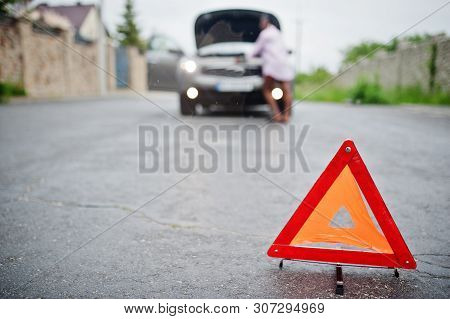 Young Sad African Woman Stand With Emergency Triangle Against Car With Popped Hood. Transportation,