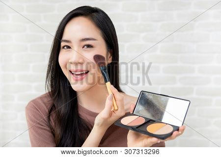 Young Beautiful Smiling Asian Woman Applying Blush Makeup On Her Cheek