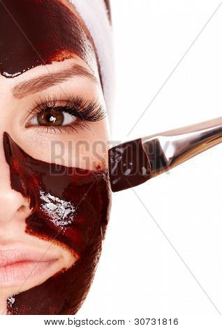 Meisje met chocolade gezichts masker toepassen door schoonheidsspecialiste.