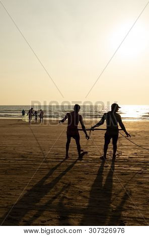 Goa, India - December 20, 2018: Fishermen Fishing With Nets On Morjim Beach