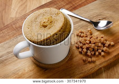 Delicious Fudge Sponge Pudding Shot On A Wooden Board With A Hand Full Of Fudge Pieces, In A Cup Wit