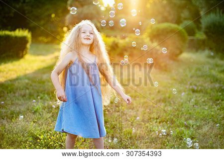 Child Whirling, Dancing Plays On The Meadow. Girl Having Fun With Bubbles. Cute Little Longhair Blon