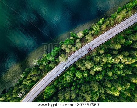 Aerial View Of Road Between Green Forest And Blue Lake In Finland