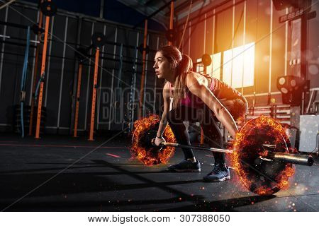 Athletic Girl Works Out At The Gym With A Fiery Barbell