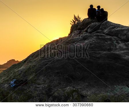 Om Beach,gokarna,karnataka/india-febuary 2, 2018:young Men Sit On The Rocks Enjoying The Setting Sun