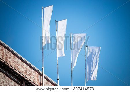 Three Blank White Flags On Flagpoles Against Cloudy Blue Sky With Perspective, Corporate Flag Mockup