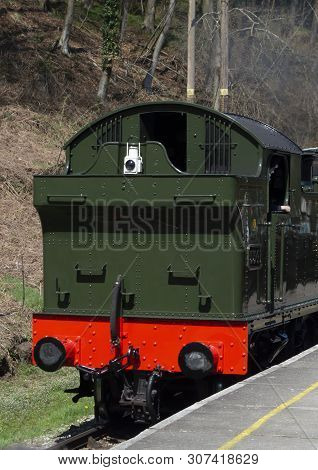 Green And Red Back Of Steam Train Engine Moving Next Tp Platform