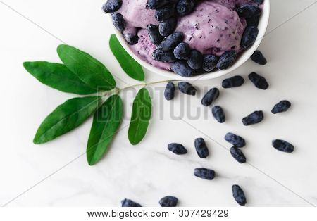 Ice-cream Decorated With Fresh Berries Of A Honeysuckle And Green Leaves On White Background. Top Vi