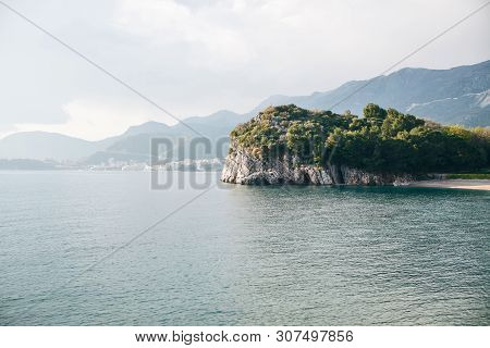 View Of The Natural Landscape. Sea, Rocky Shore With Trees Off The Coast Of Montenegro. In The Dista