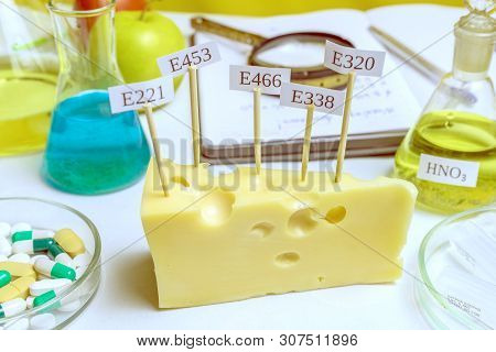 In The Cheese Are Signs With The Code E-supplements. Nearby On The Table Is A Flask Of Nitric Acid -
