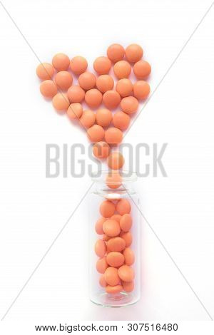 Heart Made Of Orange Tablets And Glass Bottle On White Background. Epidemic, Painkillers, Healthcare