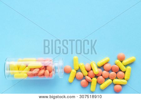 Yellow And Orange Capsules From Glass Bottle On Blue Background. Copyspace For Text. Epidemic, Paink