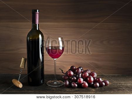 Glass And Bottle Of Red Wine On Wooden Background