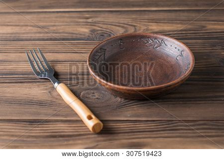 Clay Bowl On A Brown Wooden Table. Pottery For The Kitchen.