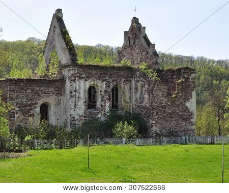 An Old Destroyed Brick Building With Broken Arched Windows. From The Roof Were Only Gables. Against 